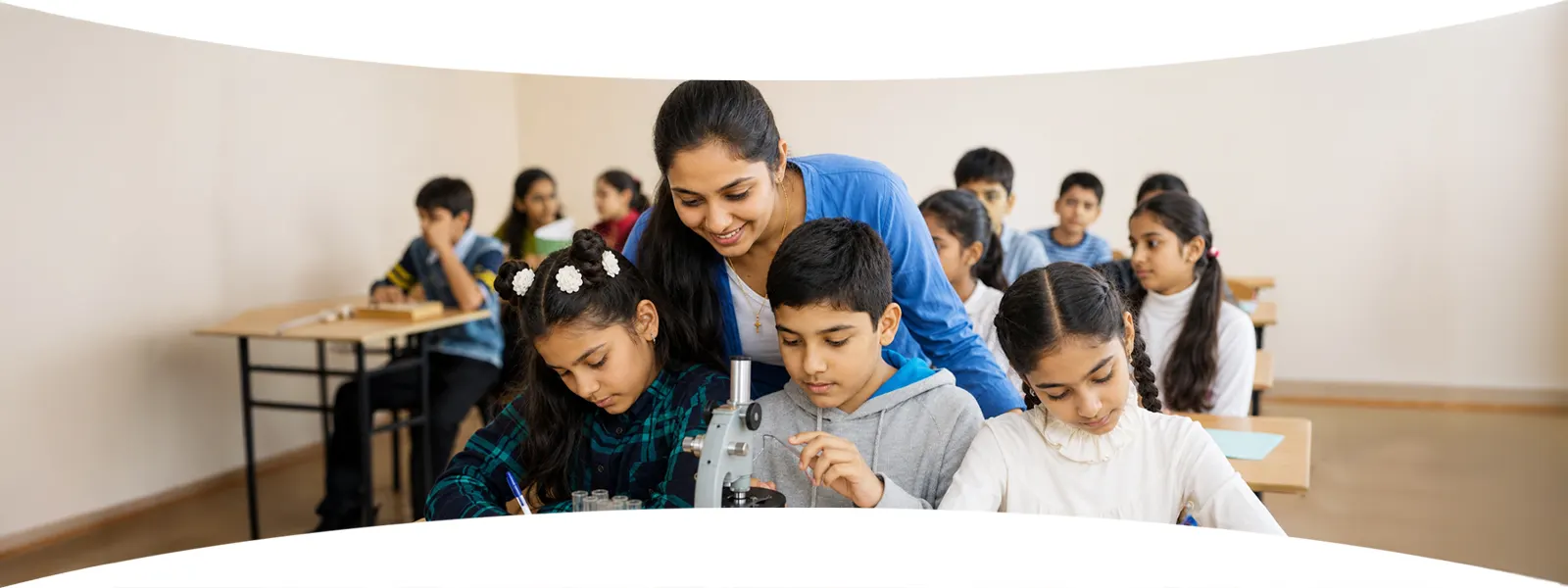 A teacher guiding Jain Heritage School students through a microscope experiment